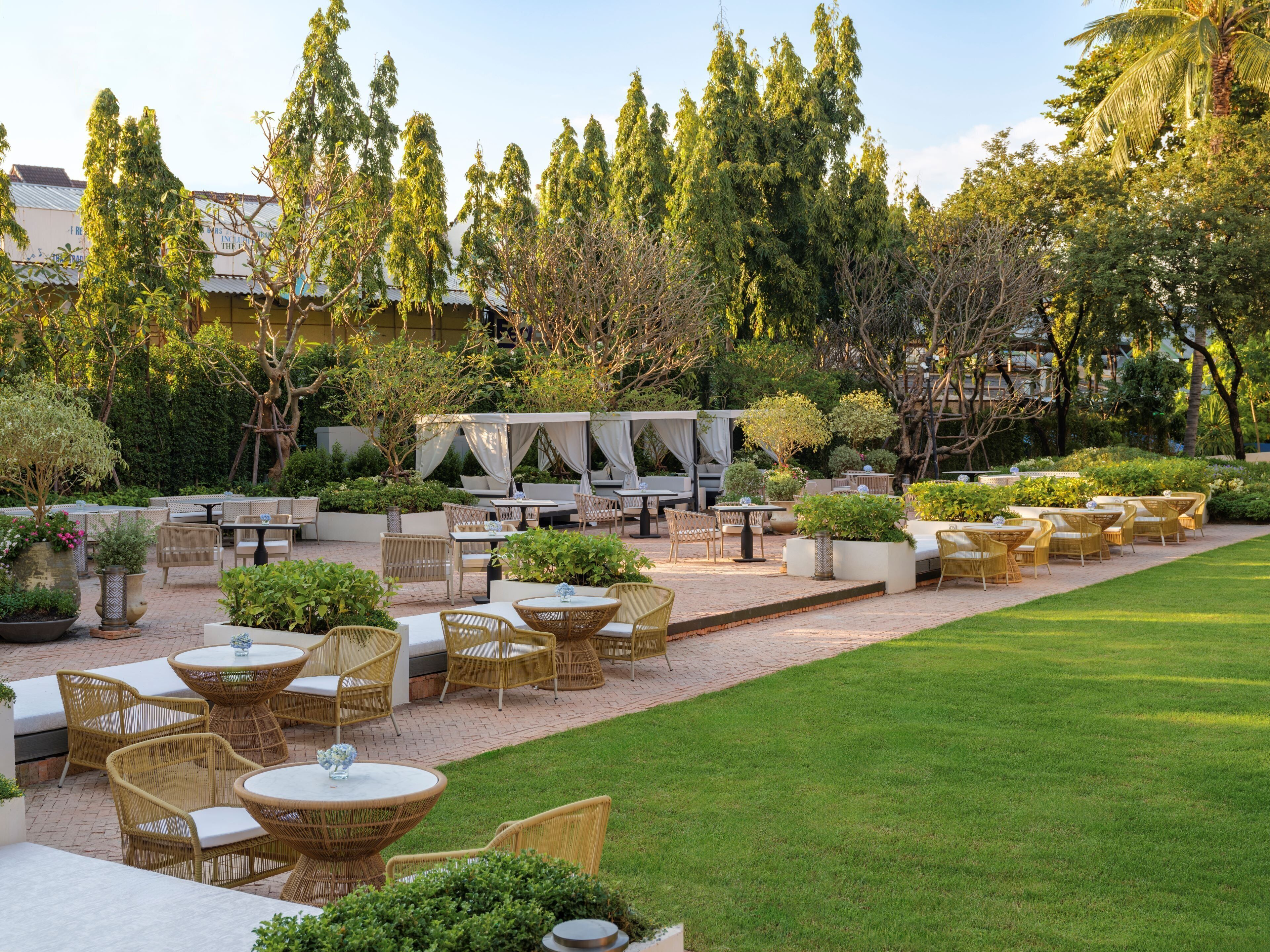 An outdoor patio with wicker furniture, a grassy lawn, and trees.