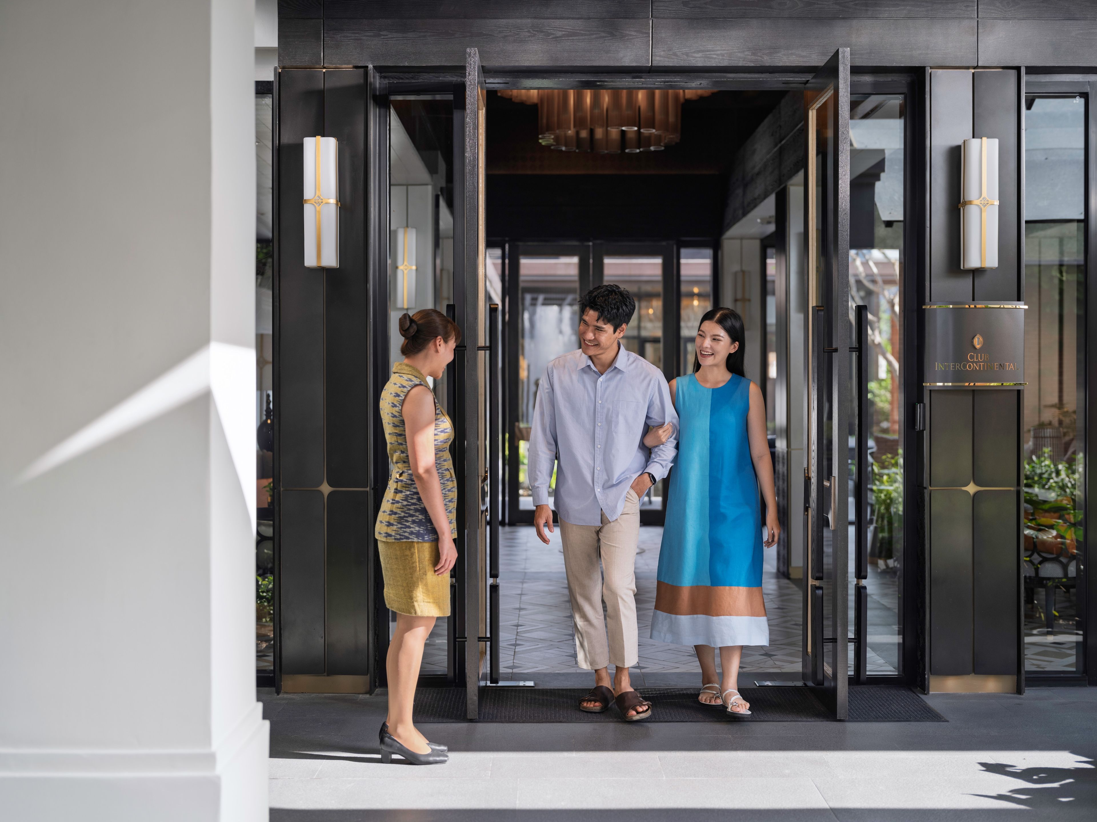 A hotel entrance with a revolving door, a reception desk, and a sign indicating the hotel name.