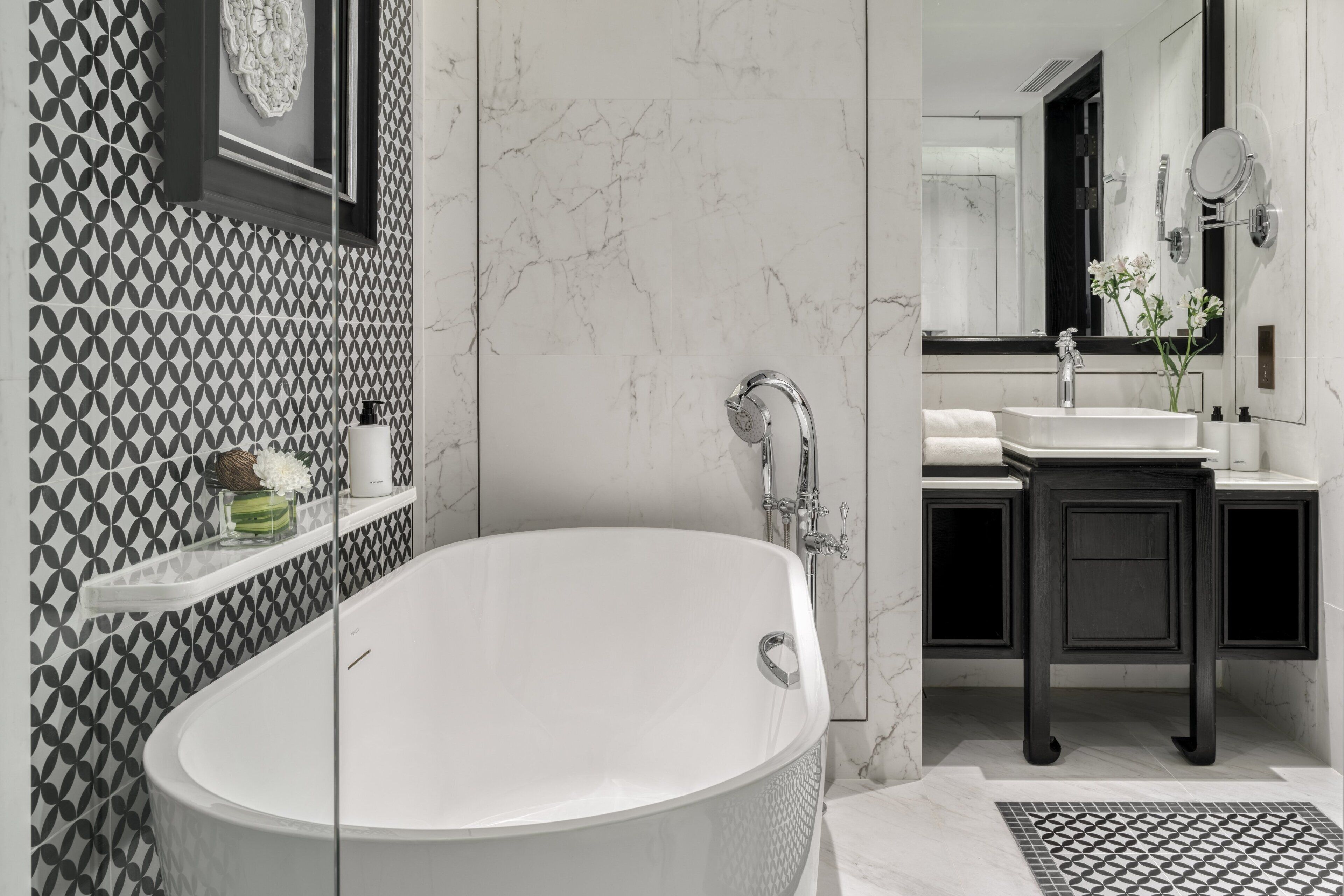 A modern bathroom with a freestanding bathtub, a vanity with a mirror, and a patterned wall.