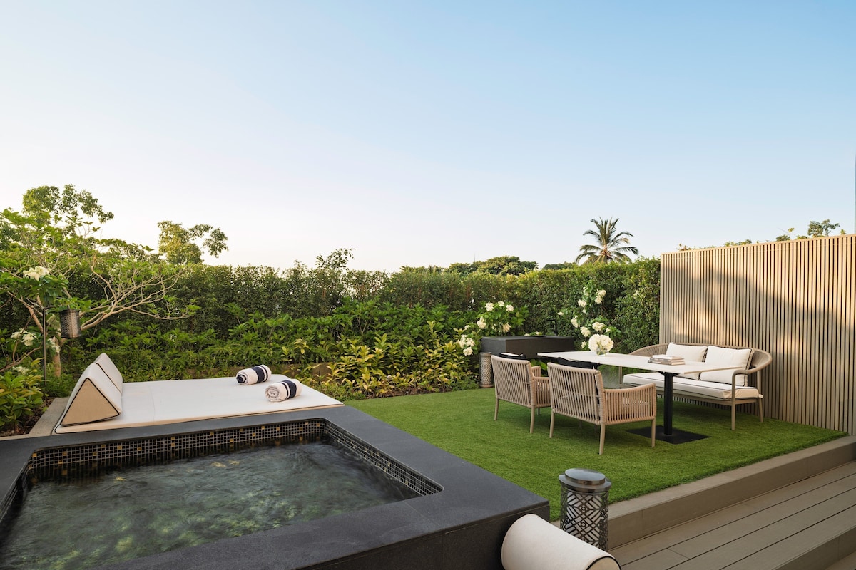Ein Whirlpool mit Fliesenverkleidung, ein Tisch mit Stühlen und eine Holzterrasse.