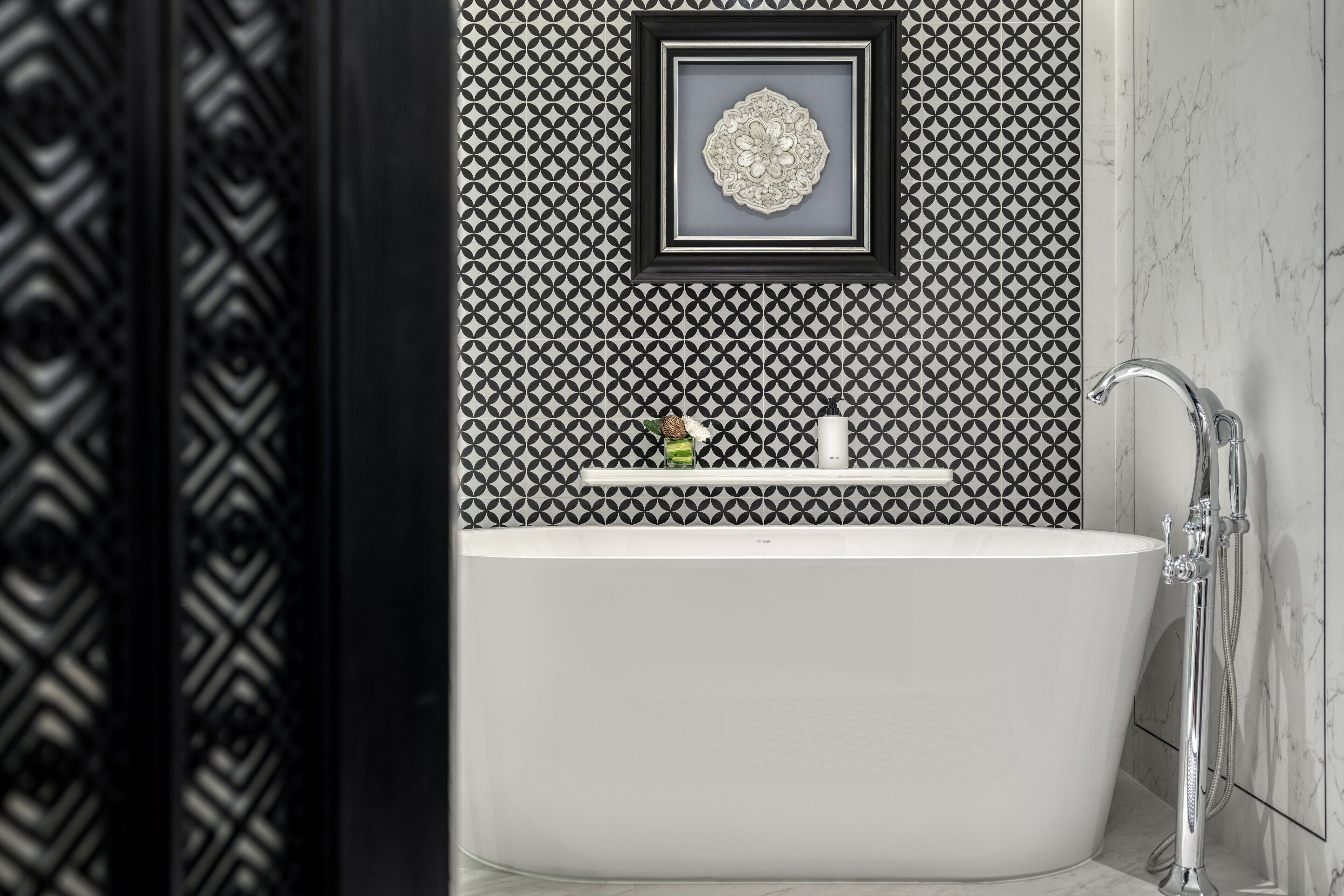 A modern bathroom with a freestanding bathtub, a framed decorative piece on the wall, and a shower area.