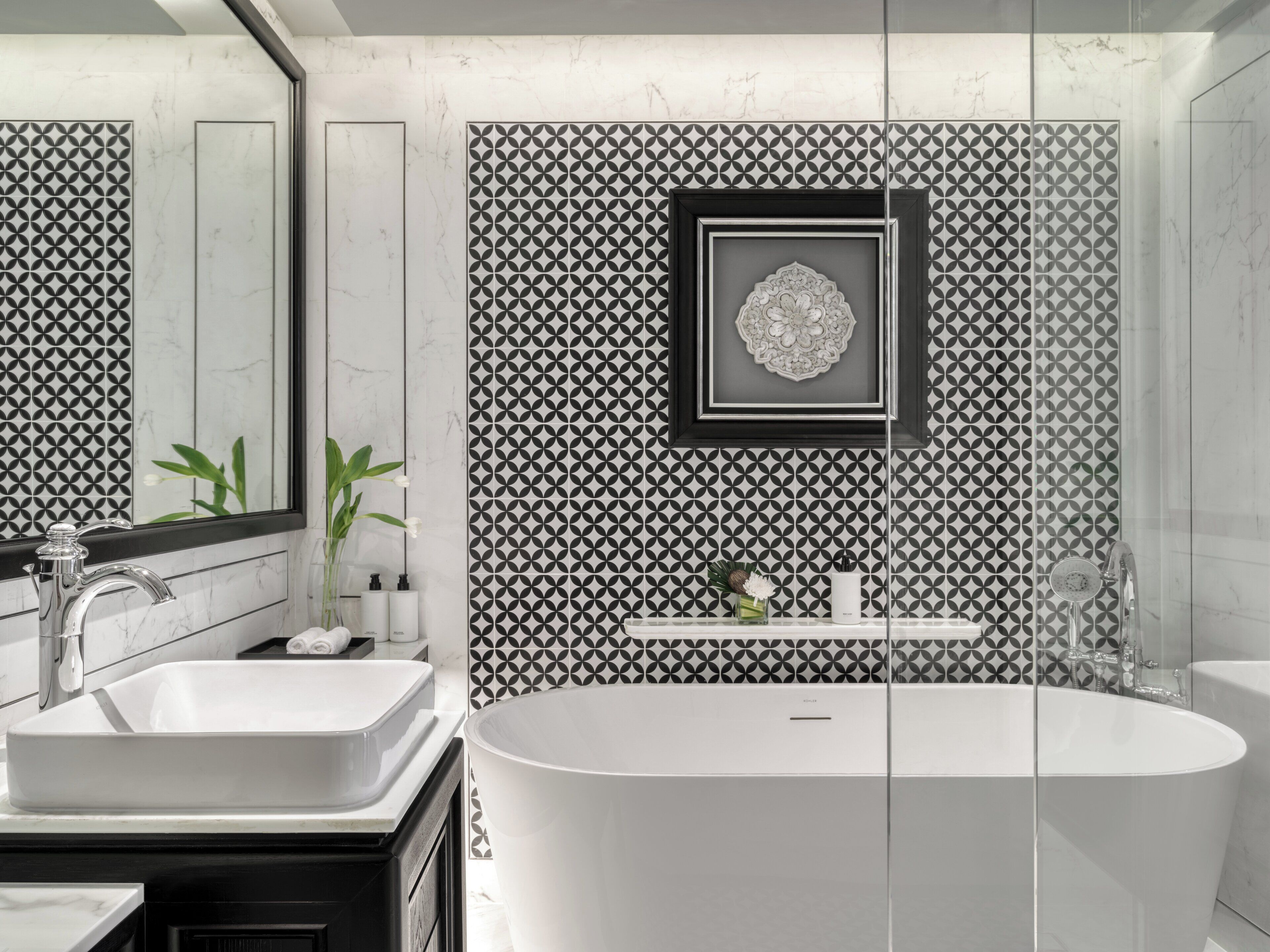 Un baño moderno con una bañera independiente, dos lavamanos y un panel decorativo en la pared.
