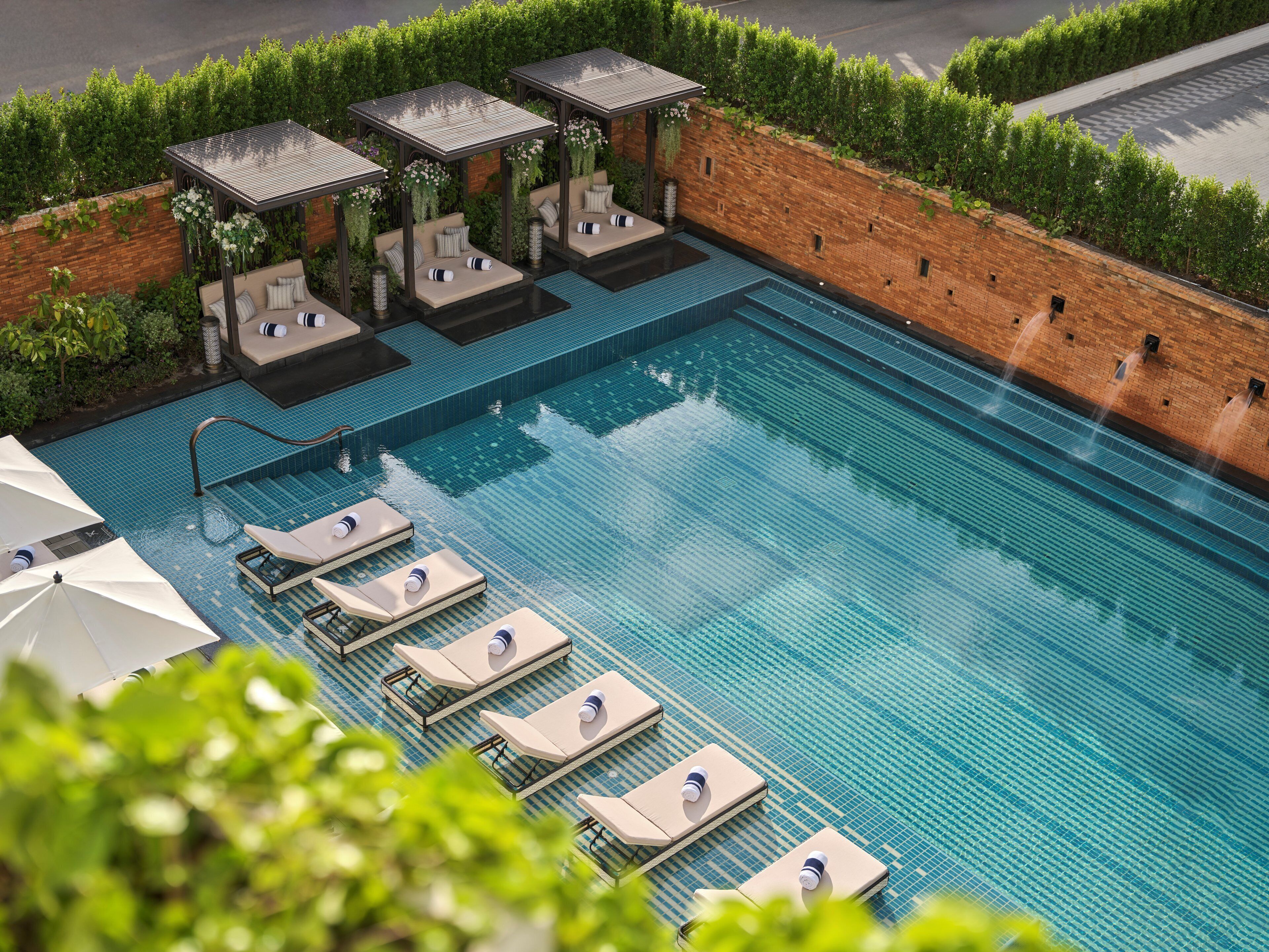 A rooftop swimming pool with lounge chairs and covered seating areas.