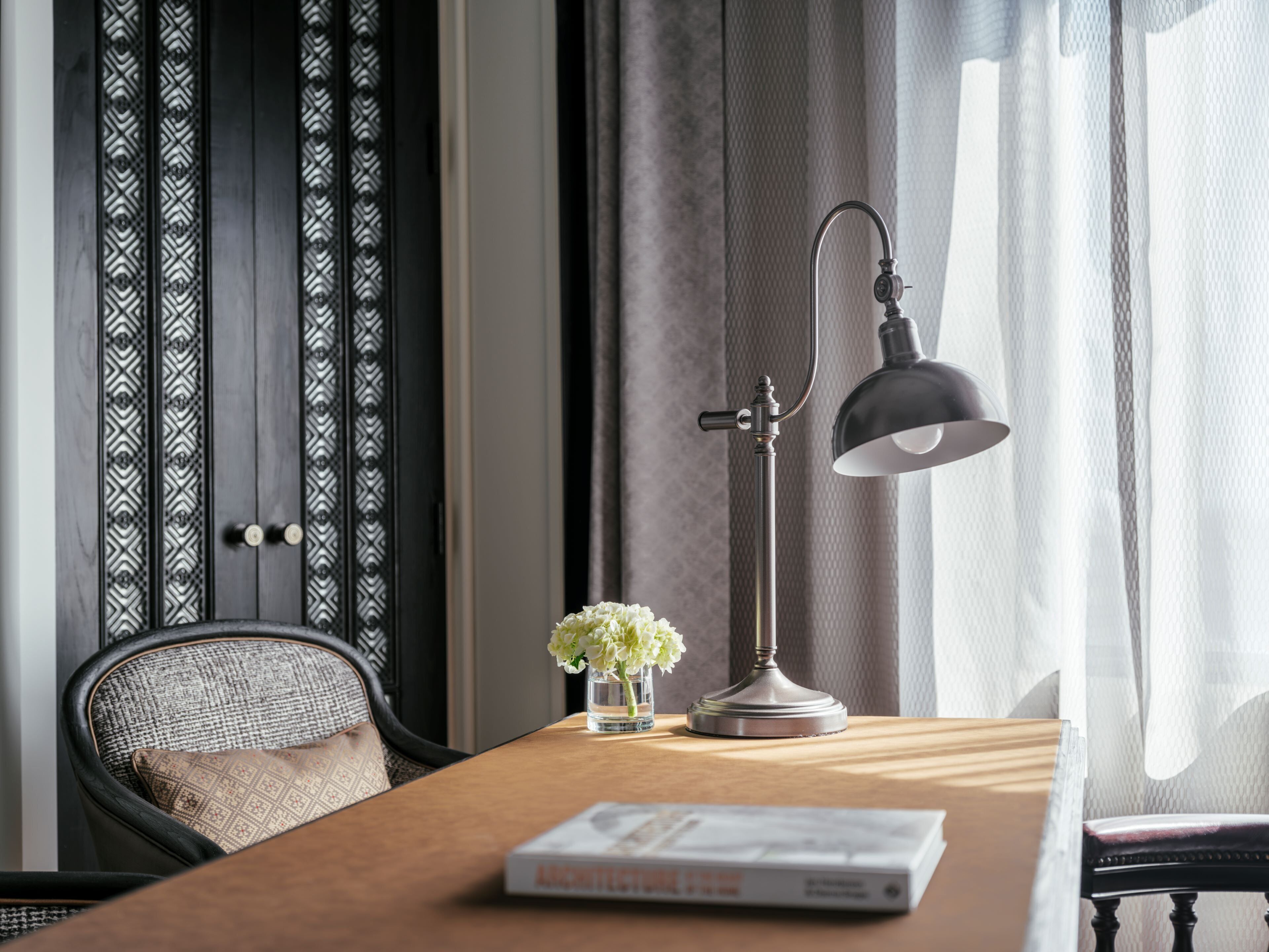 Una mesa de madera con una lámpara, un jarrón con flores y una revista.