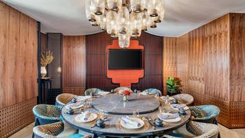 Una mesa redonda para comer con un candelabro moderno, rodeada de sillas tejidas, lista para una comida.