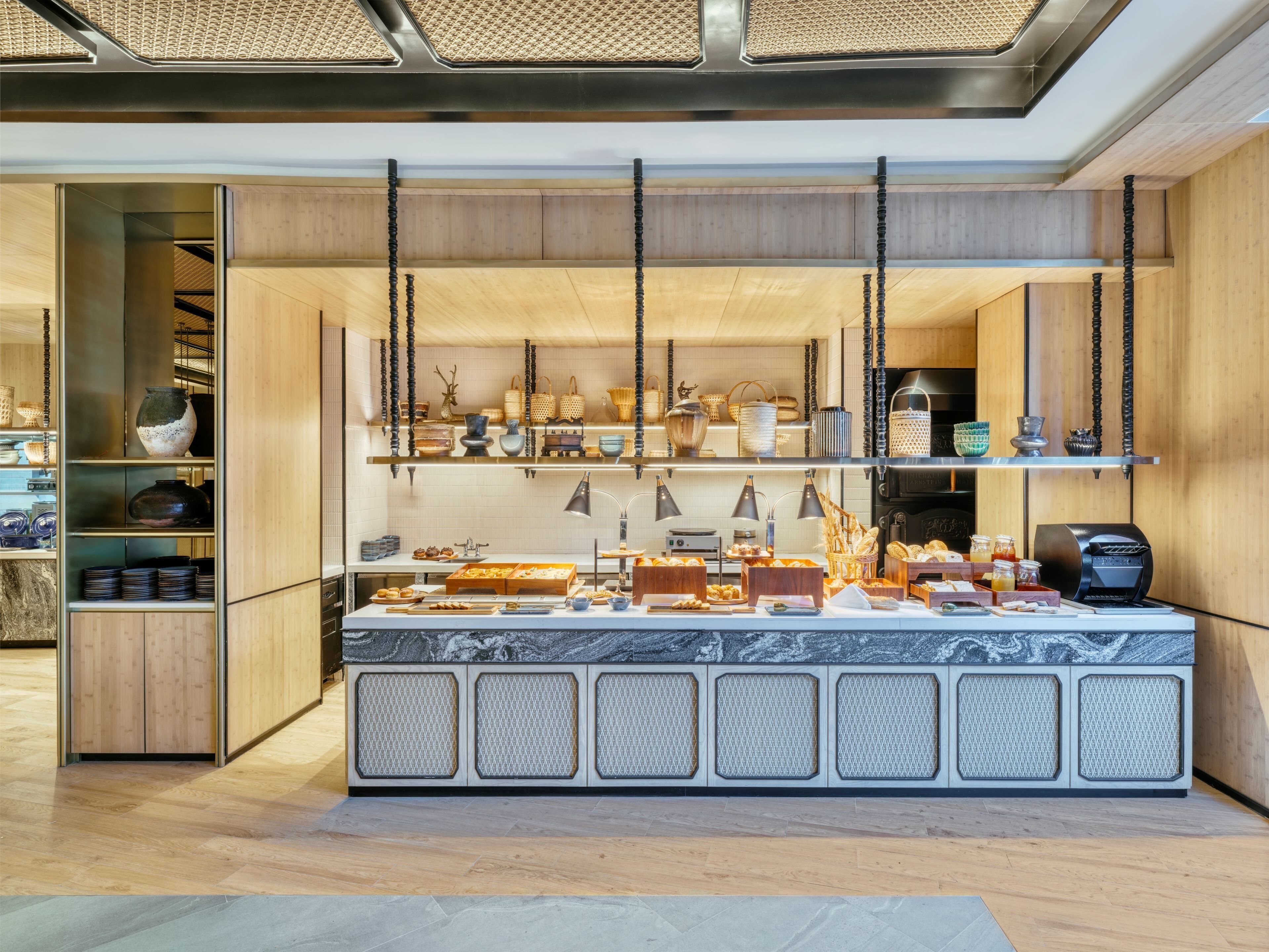 Cocina moderna con armarios de madera, encimera de mármol y cestas colgantes.