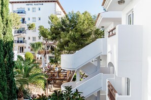 A hotel with multiple floors, outdoor seating areas, and lush greenery.