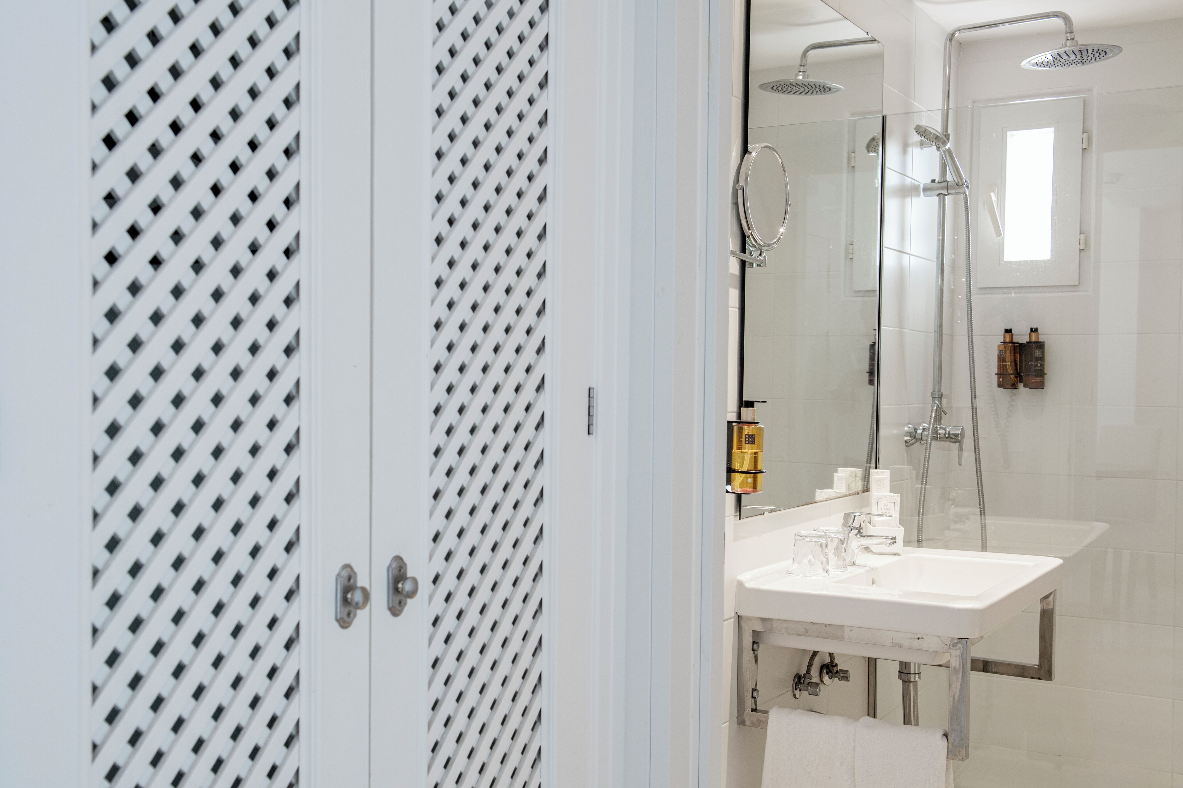 Un baño moderno con un espejo grande, un lavamanos blanco y una zona de ducha.