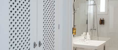 A modern bathroom with a large mirror, a white sink, and a shower area.