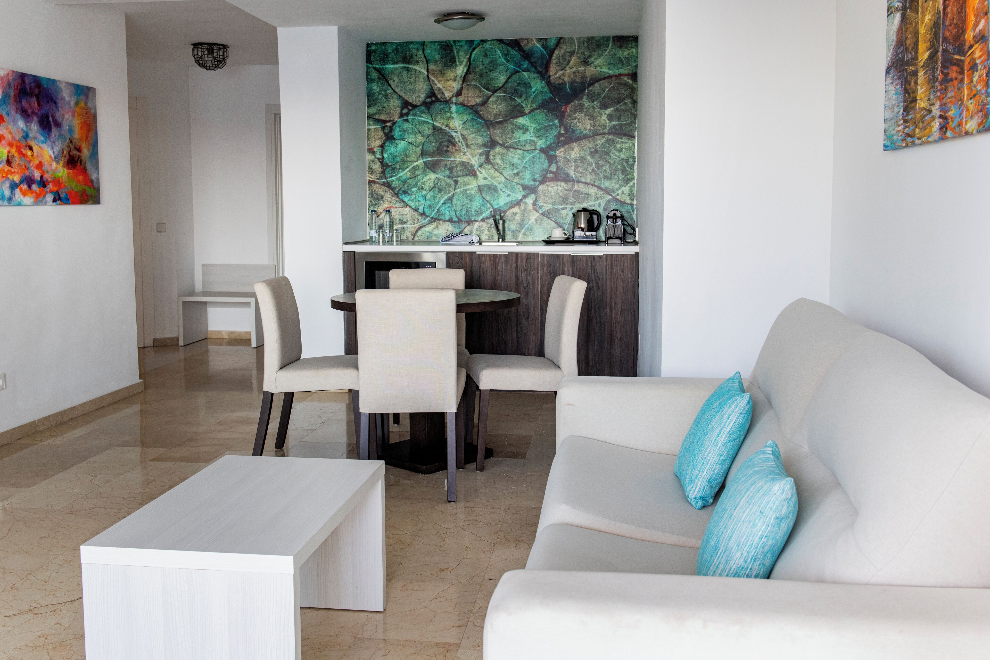 A modern living room with a white sofa, a coffee table, and a dining area with a table and chairs.