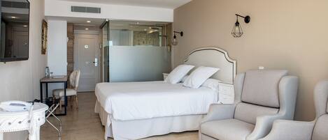 Ein Hotelzimmer mit einem Bett, zwei Sesseln, einem Schreibtisch und einem Spiegel.