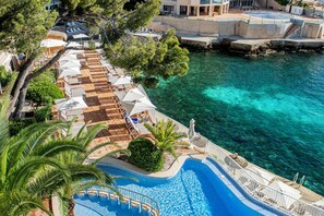 An infinity pool with a view of the sea, lounge chairs, and umbrellas.