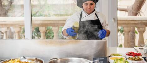A chef preparing food in a kitchen with various dishes and cooking utensils visible.