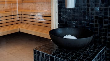 Een sauna met houten banken en een wand van zwarte tegels.