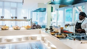 Montaje de bufé con varias estaciones de comida y un chef preparando alimentos.