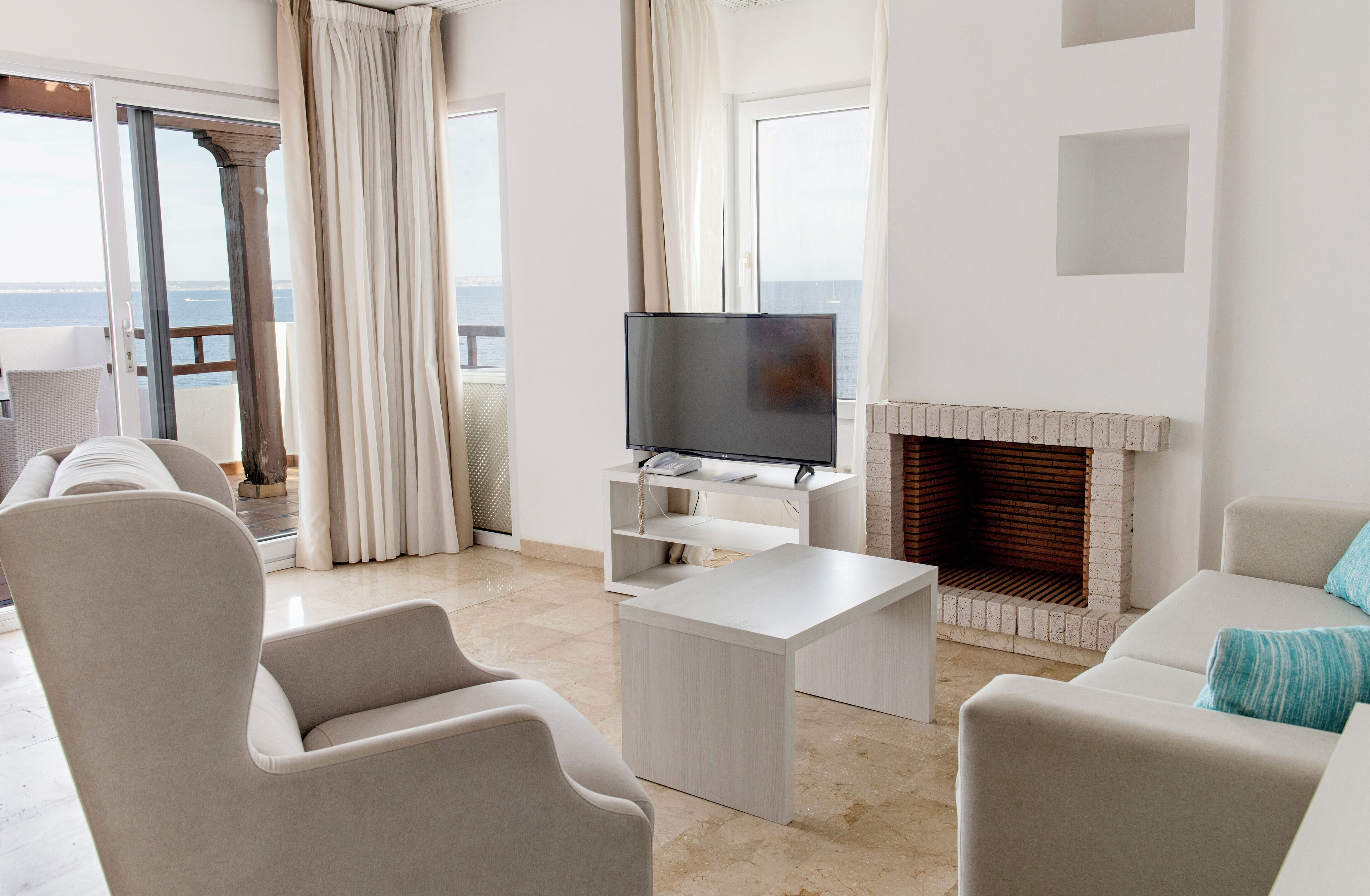 Una sala de estar moderna con un televisor de pantalla plana, una chimenea y un balcón con cortinas.