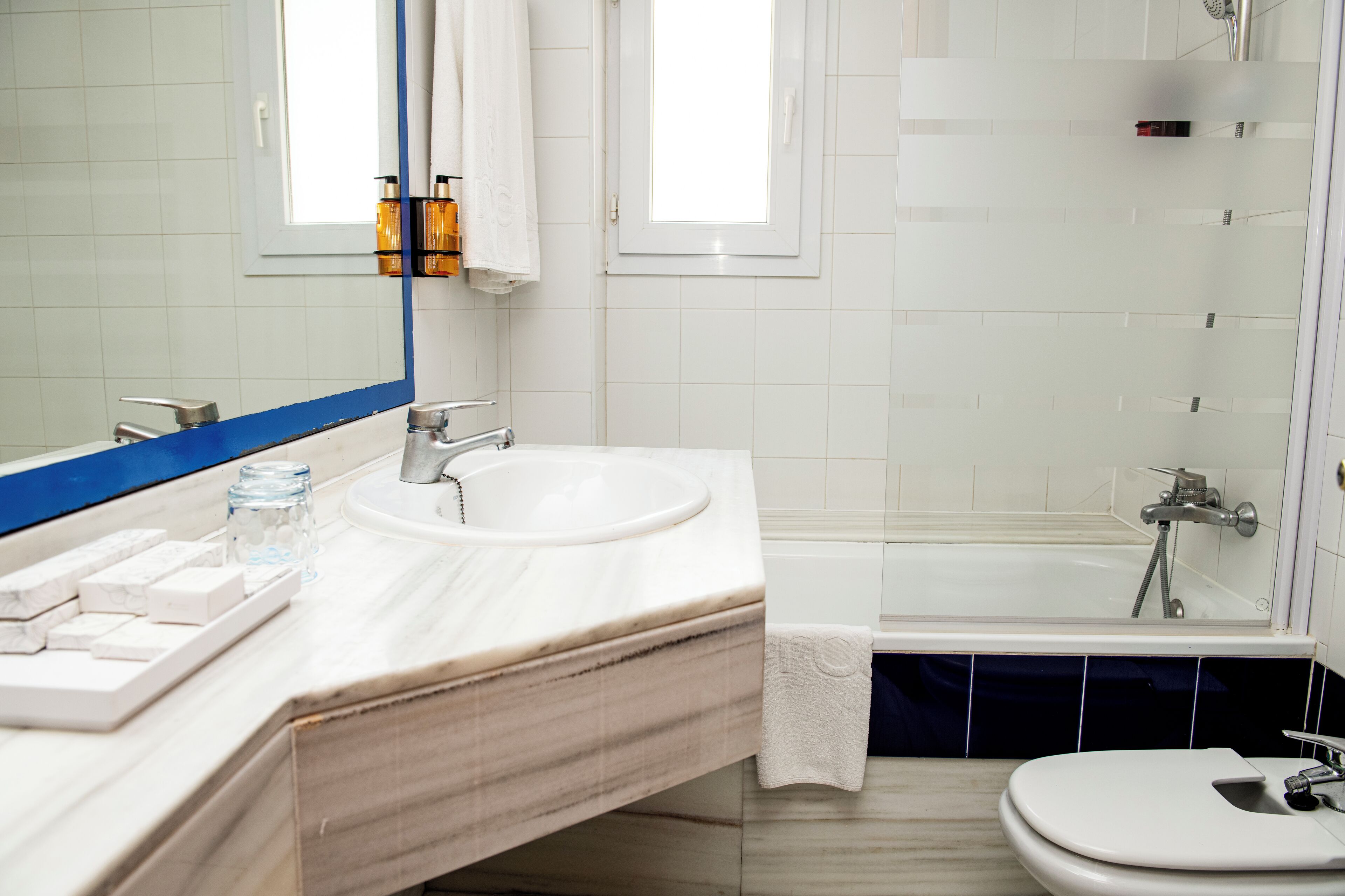 Un baño con un lavamanos blanco, un espejo, una bañera y un inodoro.