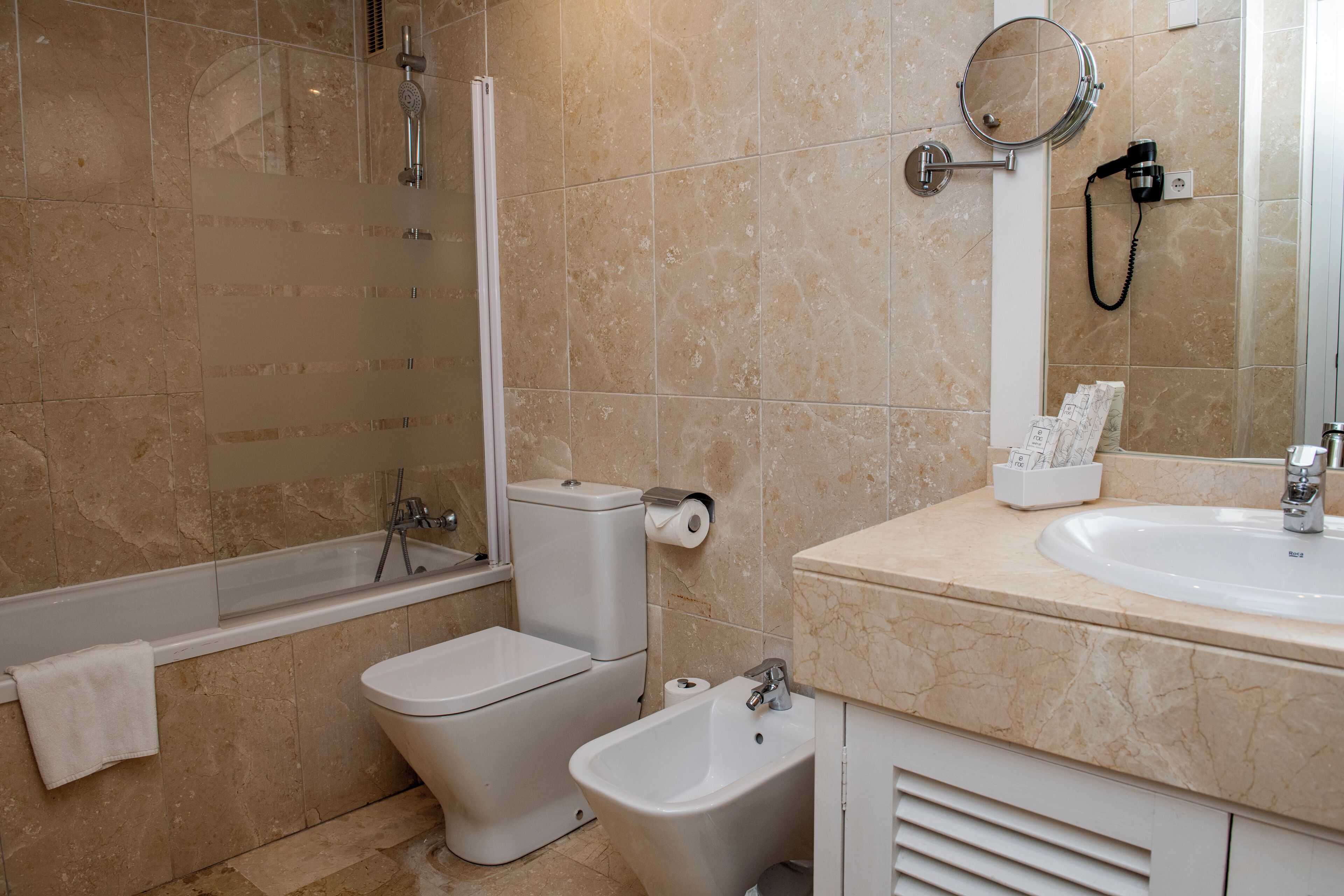 A bathroom with a bathtub, toilet, bidet, and a sink with a mirror.