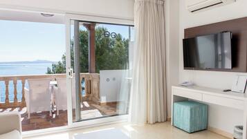Habitación de hotel moderna con balcón, televisión y un pequeño rincón de estar.