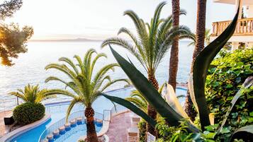 Una piscina al aire libre, sombrillas, sillones reclinables de piscina