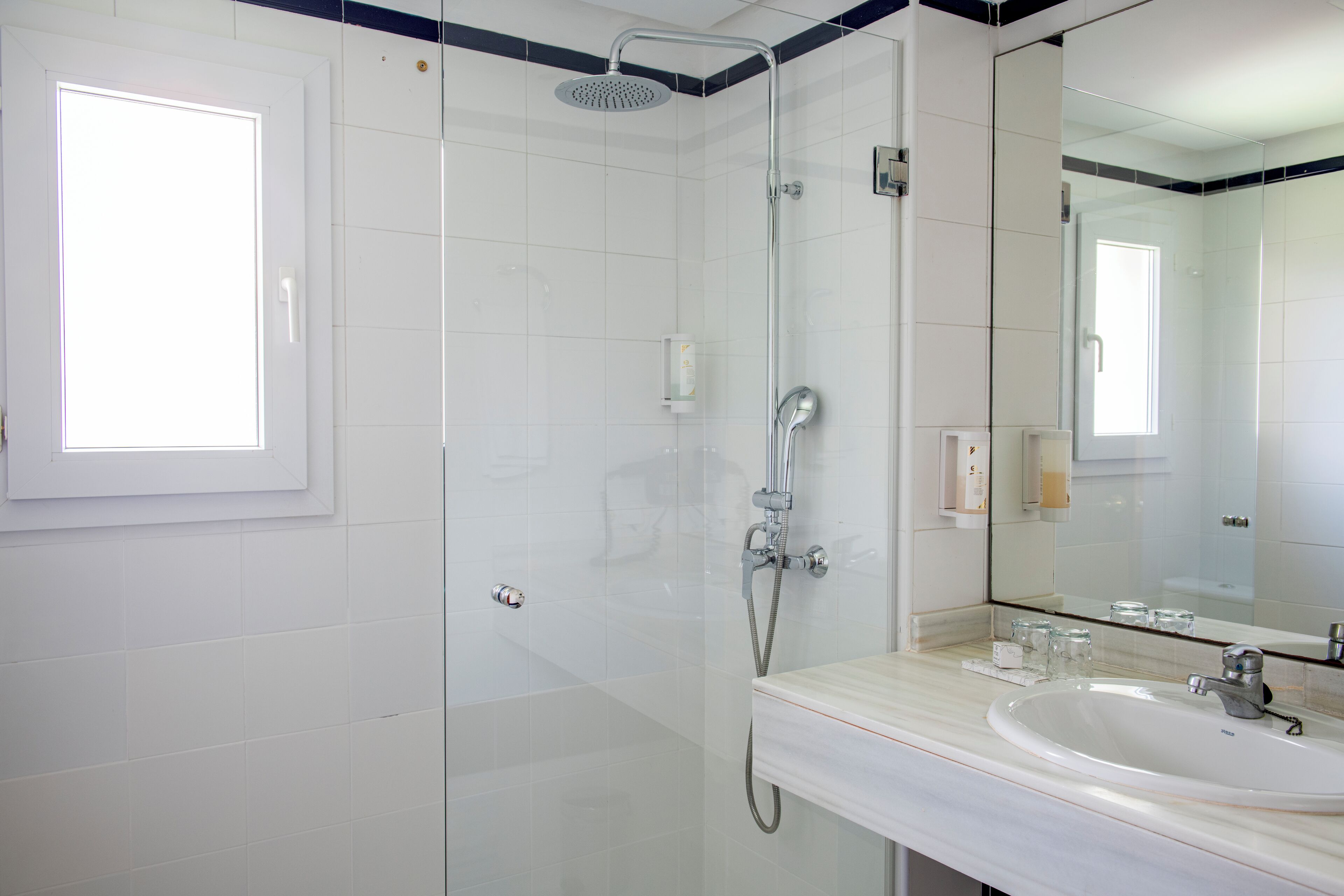 Een moderne badkamer met een douchecabine van glas, een witte wastafel en een grote spiegel.