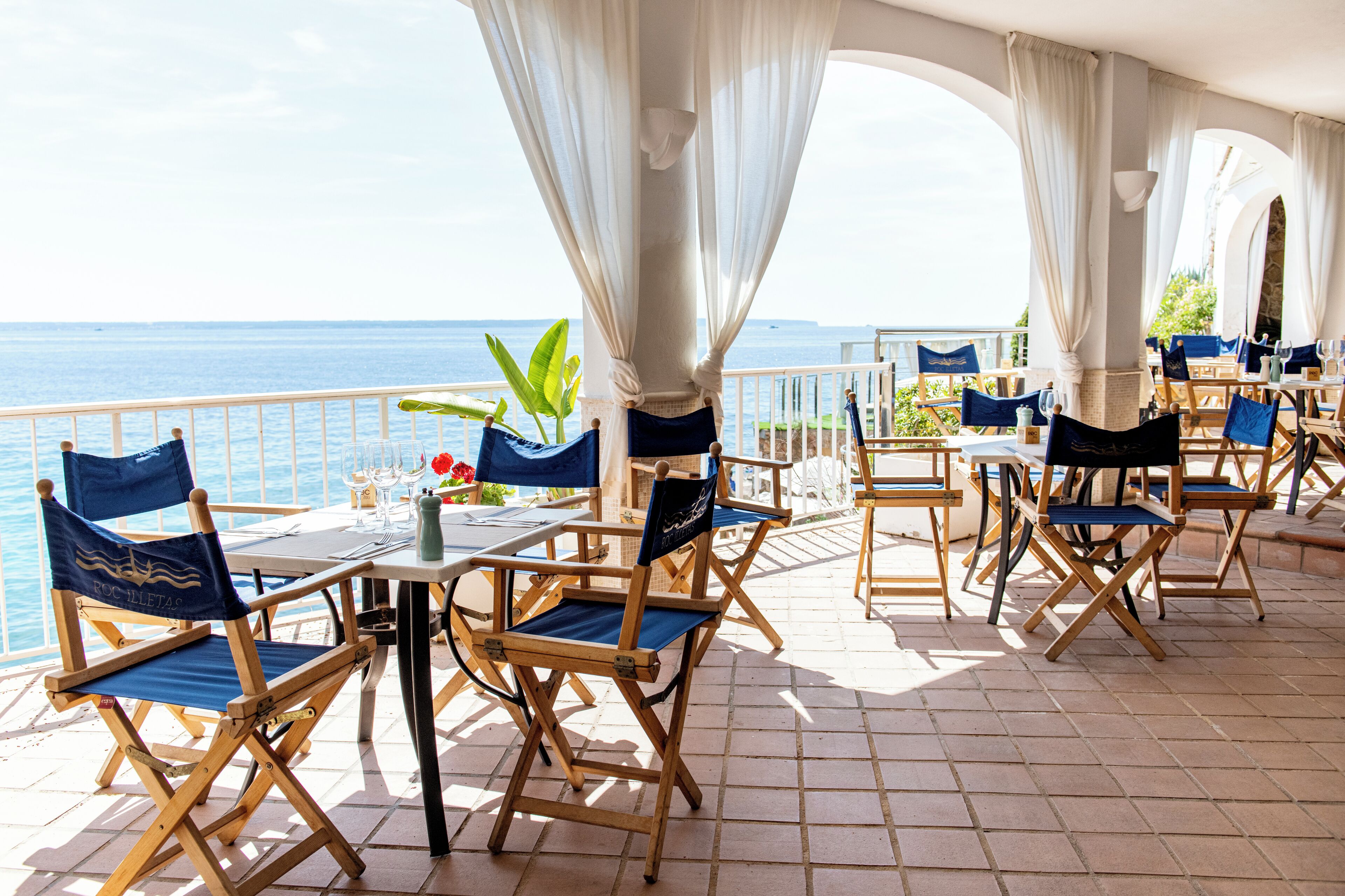 Une terrasse dotée de chaises et de tables en bois, offrant une vue sur la mer.