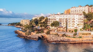 Un hotel frente al mar con varios balcones, una costa rocosa y vistas al océano.