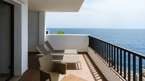 Un balcón con dos sillones de descanso y una mesita, con vista al mar.