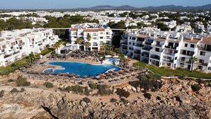 Un resort con piscina, edificios de varios pisos y un paisaje rocoso.
