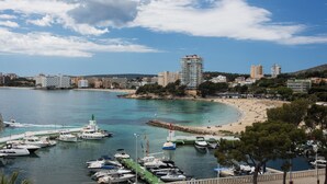 A marina with boats docked, a beach with people, and buildings in the background. - Suites ROC Portonova - Newly Renovated 2026 (Calvia)