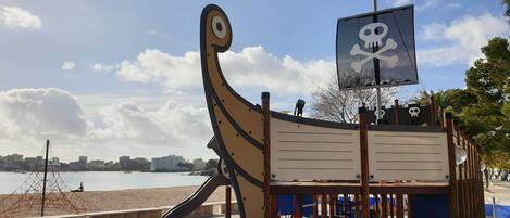 A pirate-themed play structure with a slide and a flag featuring a skull and crossbones.