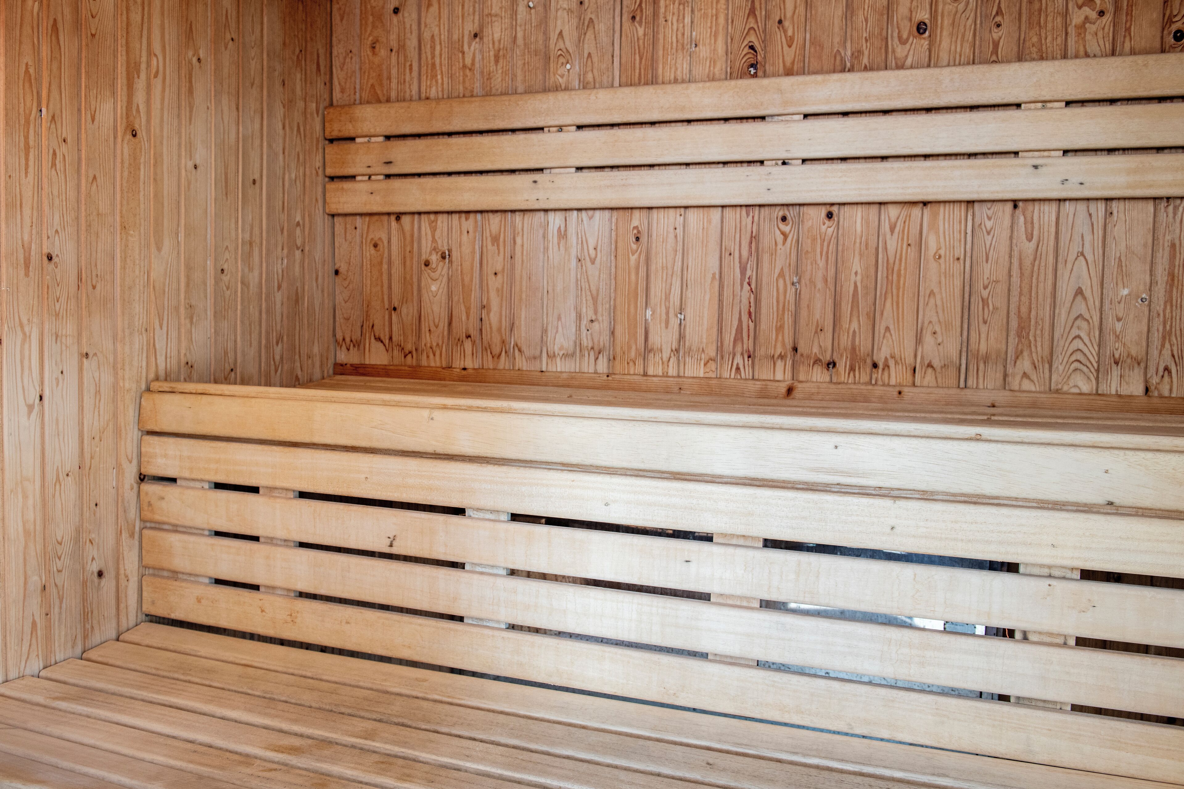Un banco de madera con listones horizontales en una habitación con paredes de madera.
