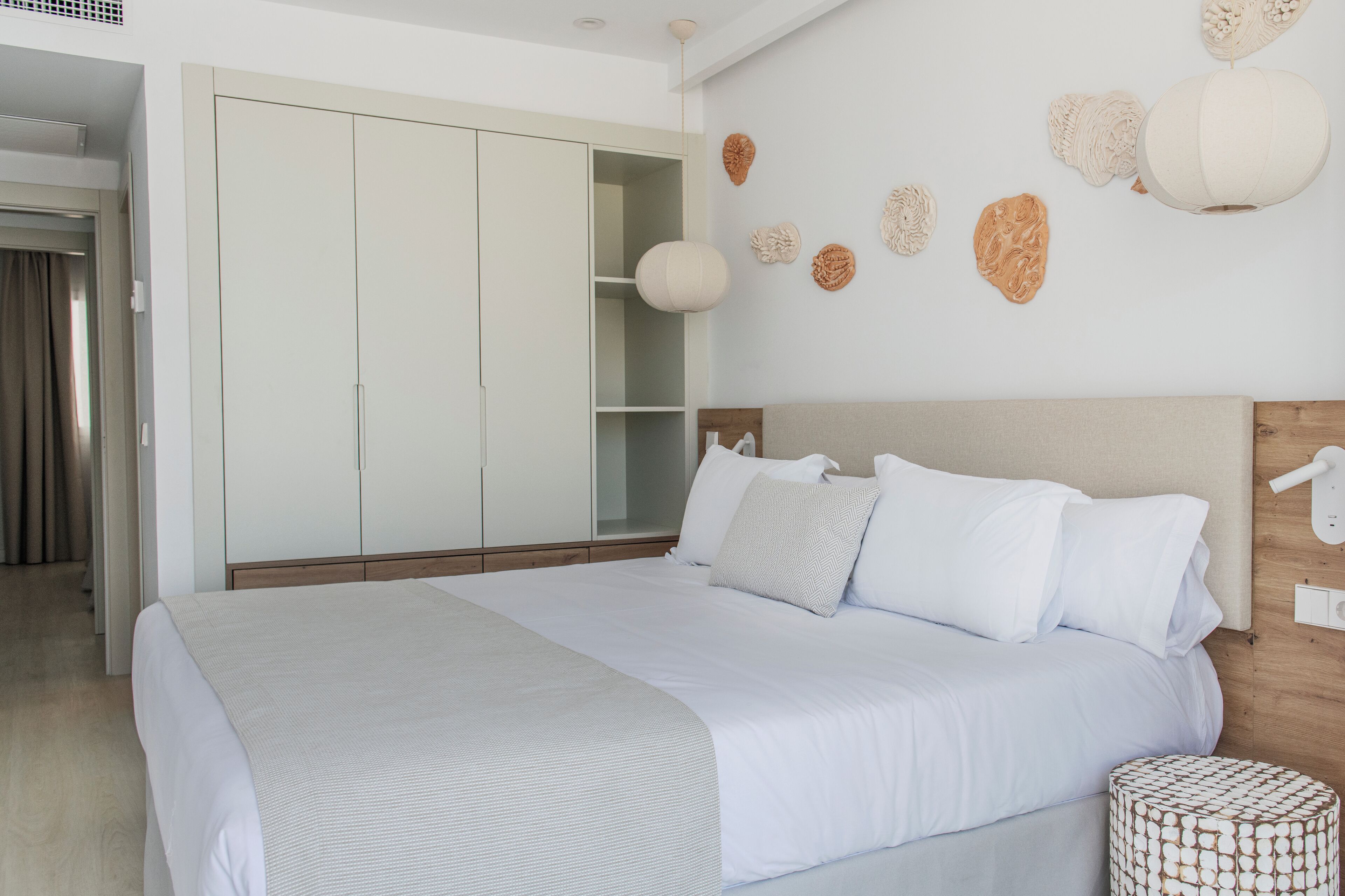 A bedroom with a large bed, a wardrobe, and decorative wall art.