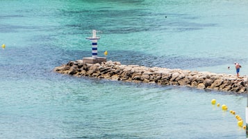Een steiger die zich uitstrekt in een heldere blauwe zee, met een vuurtoren aan het uiteinde.