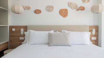A neatly made bed with white linens and a patterned pillow, a wooden headboard, and wall-mounted decorative items.