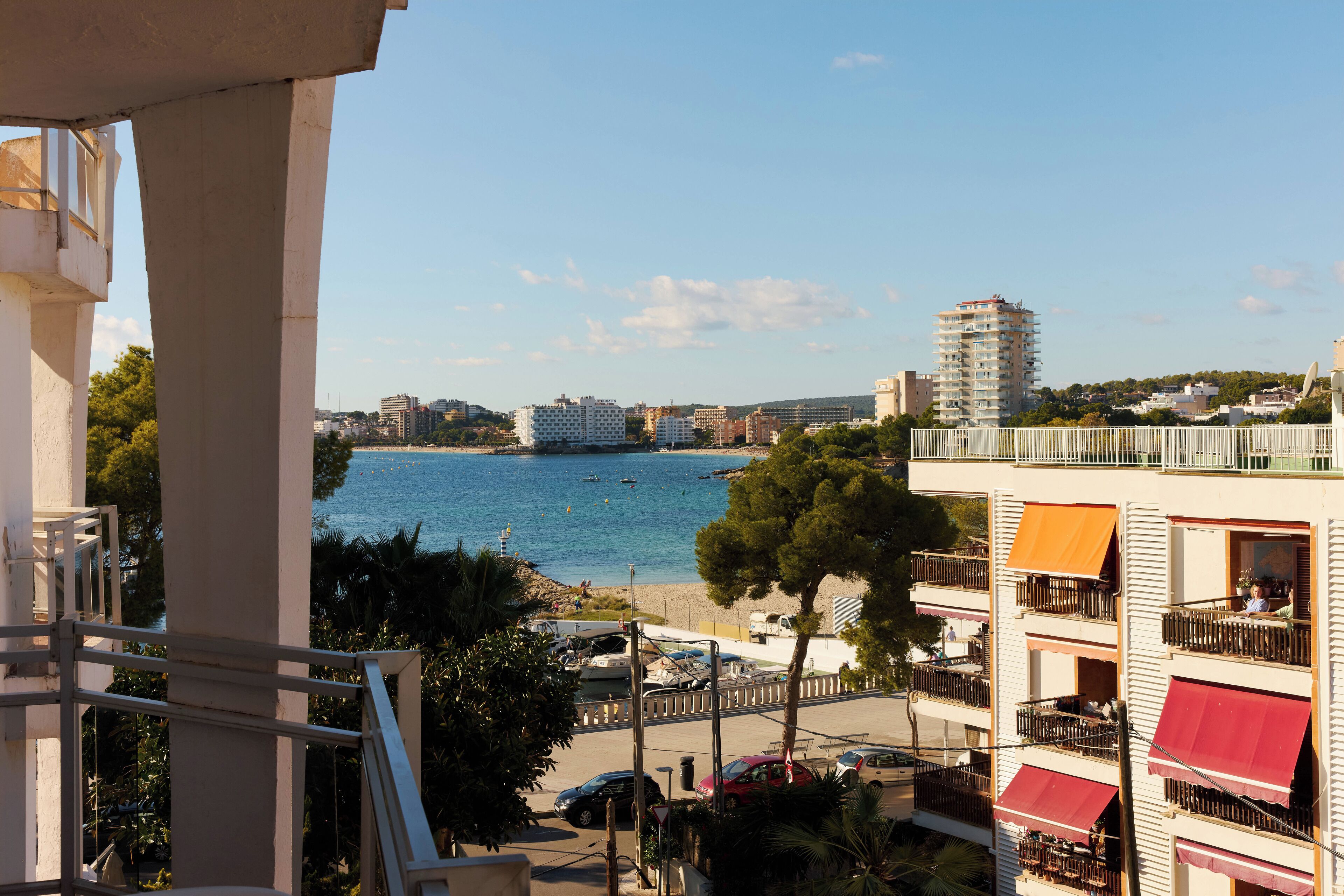Vista costera con edificios, un puerto deportivo y cielo despejado.