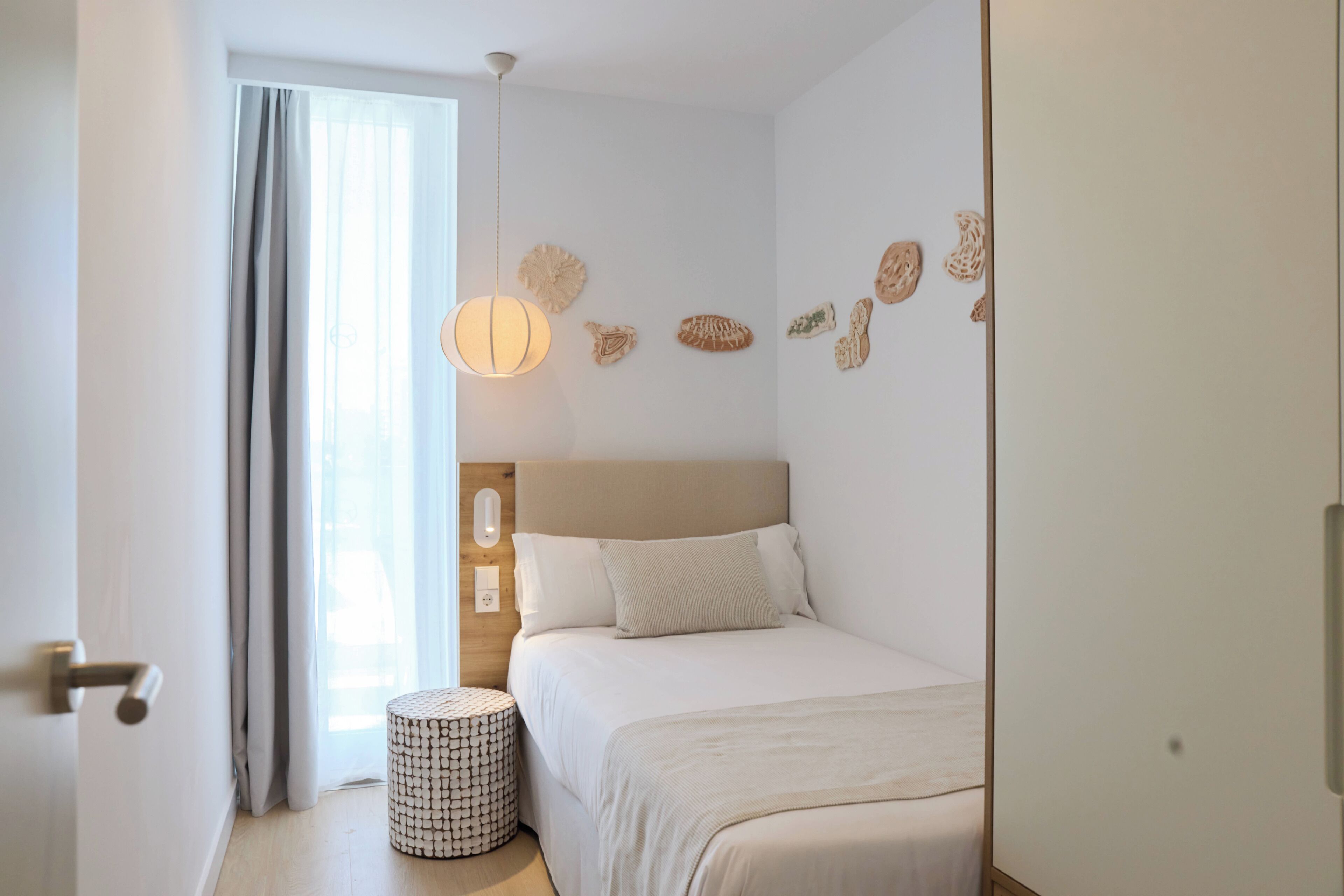 Un dormitorio con cama, mesita de noche, lámpara y decoración en la pared.