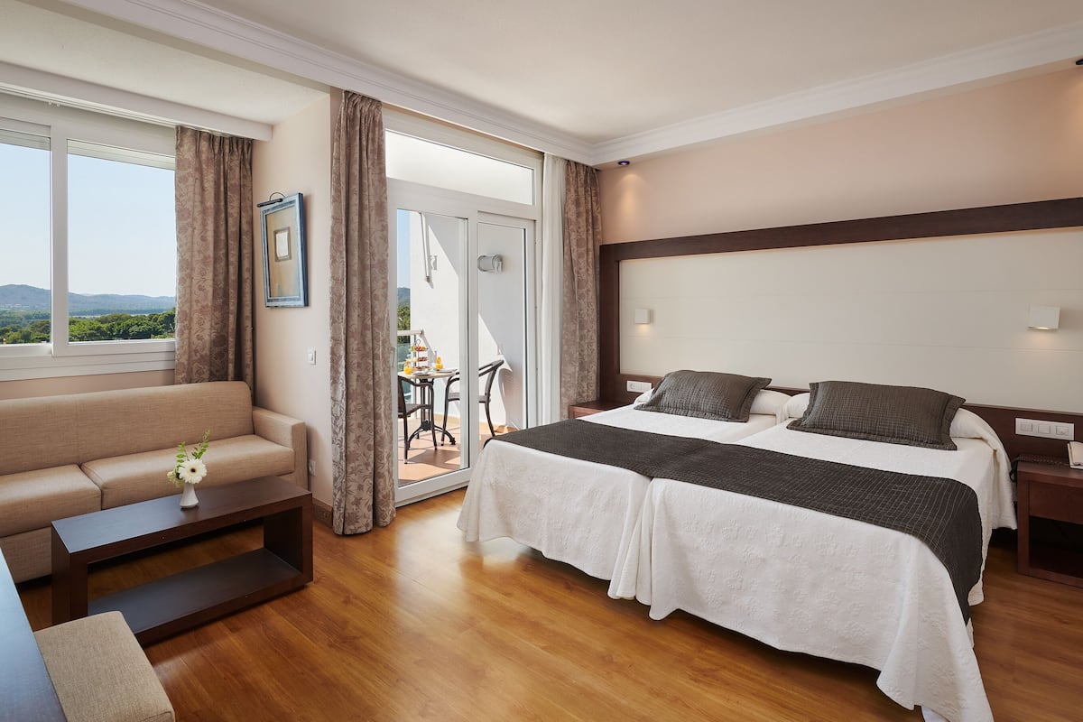 Une chambre d’hôtel dotée d’un grand lit, d’un canapé, d’une table à manger et d’un balcon offrant une vue sur les montagnes.