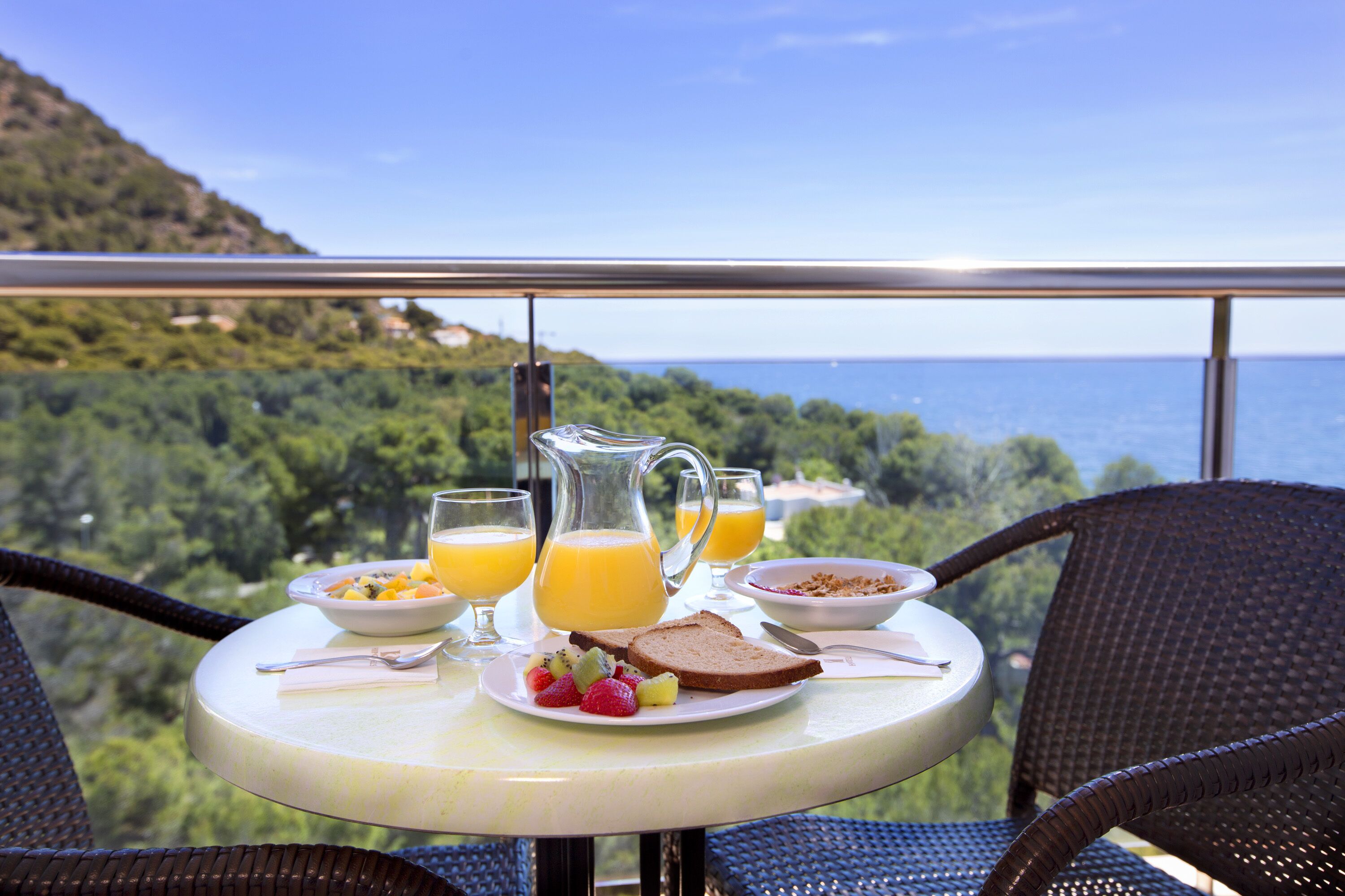 A table with breakfast items and a view of the sea.