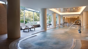 Un amplio espacio interior con piscina, ventanas grandes, asientos y una fuente central.