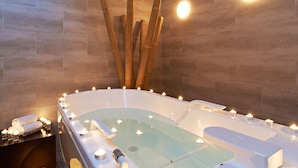 Un baño de spa con velas, un perchero y una lámpara de pared.