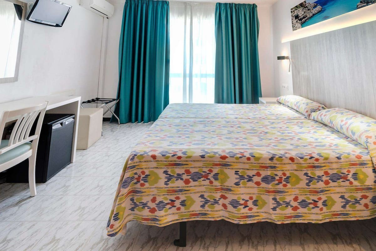 Een hotelkamer met een bed, een bureau, een stoel, een bijzettafeltje en een televisie.
