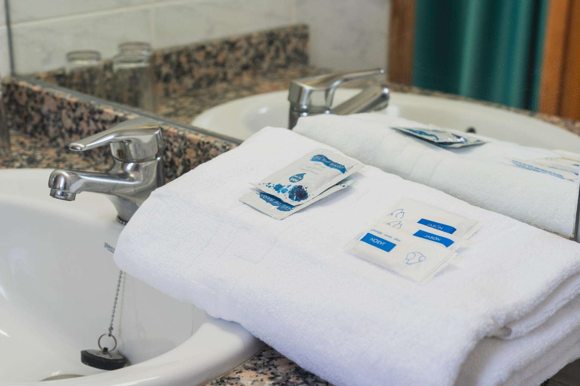 A bathroom with two sinks, each with a white towel and a soap dispenser.