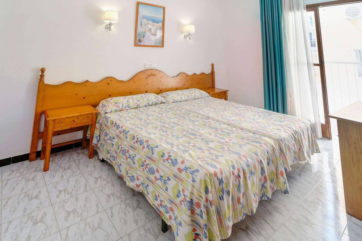 Ein Schlafzimmer mit einem hölzernen Bett, einem Nachttisch, einer Wandleuchte und einem Gemälde.
