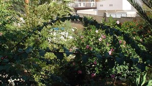 Un edificio de varios pisos con balcones, rodeado de exuberante follaje y plantas en flor.