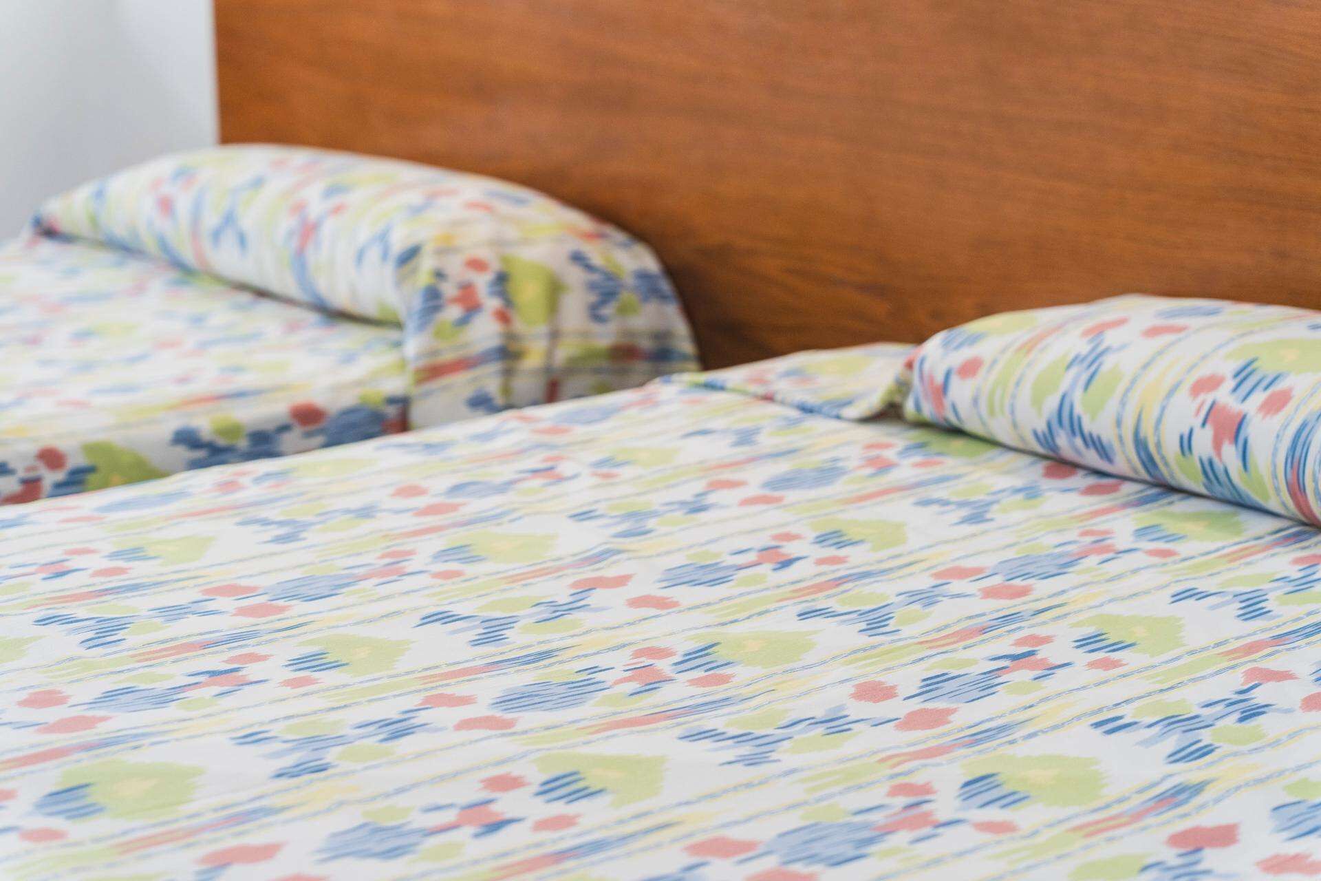 A bed with a floral patterned bedspread and matching pillows.