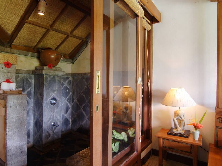 A bathroom with a stone sink, a wooden cabinet, and a glass shower enclosure.