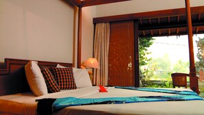 Habitación de hotel con cama, almohadas, una lámpara y vistas a zonas verdes.