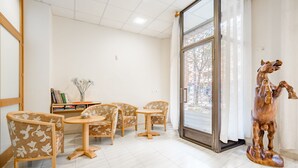 A room with a wooden horse sculpture, a glass door leading outside, and a seating area with patterned chairs and a small table. - Hotel Amic Colón (Palma de Mallorca)