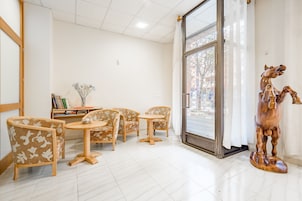 Una habitación con una escultura de un caballo de madera, una puerta de vidrio que da al exterior, y una zona de estar con sillas estampadas y una mesita.
